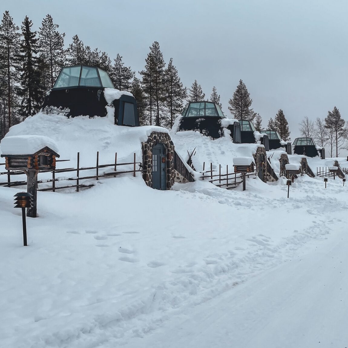 Cozy wooden cabin surrounded by snow-covered trees in Lapland, with warm lights glowing inside, perfect for a winter getaway.